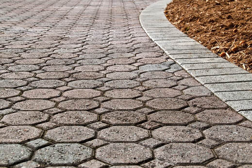 A multi-tone paver driveway with a gray brick border.